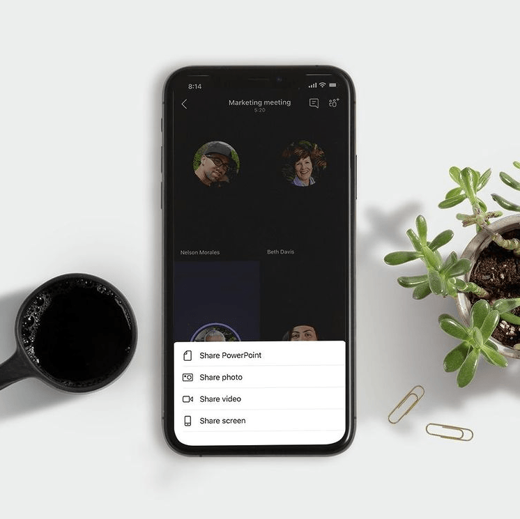 A cell phone is sitting on a table next to a cup of coffee and a potted plant.