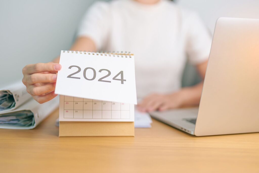 A person is holding a calendar with the year 2024 on it.