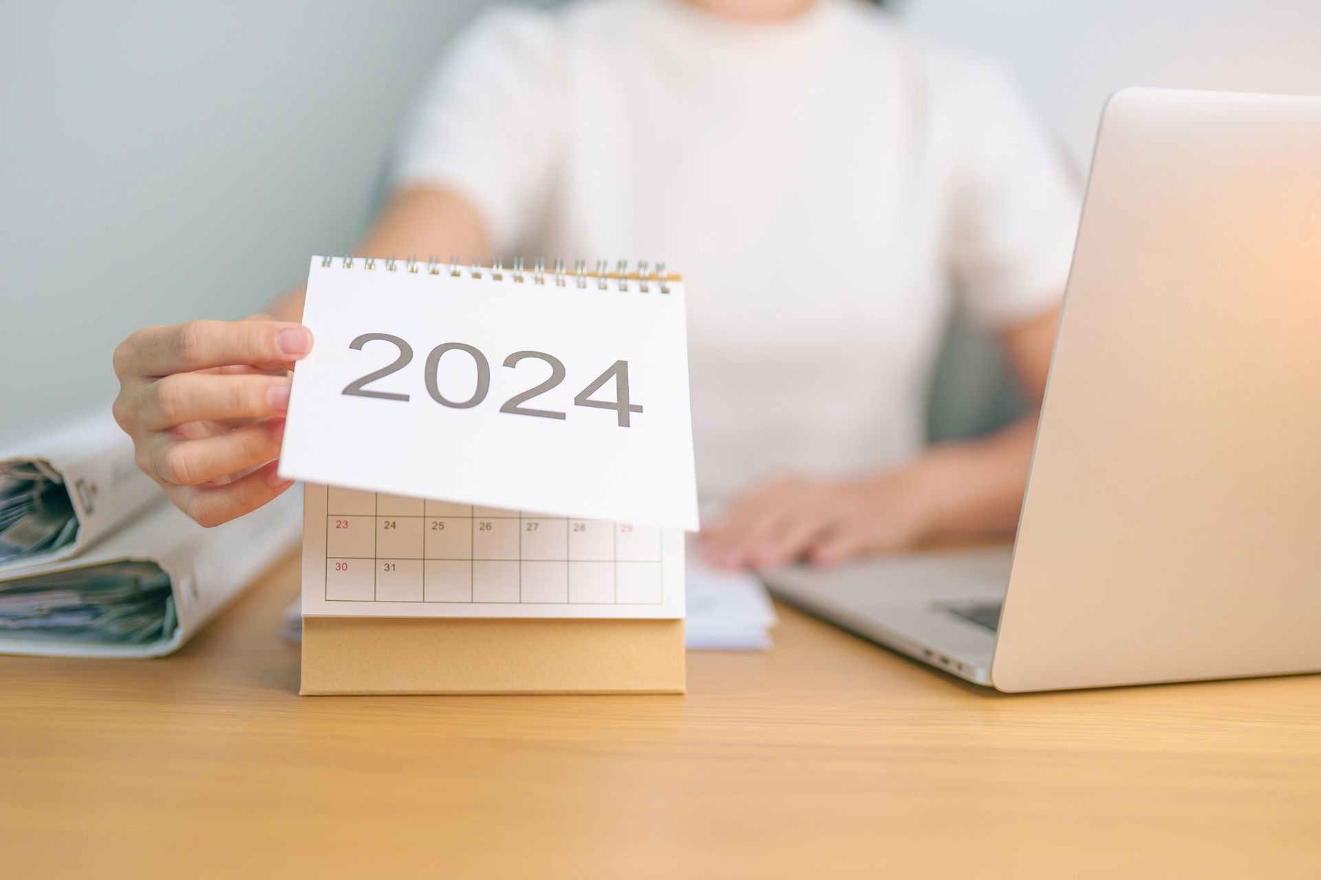 A person is holding a calendar with the year 2024 on it.