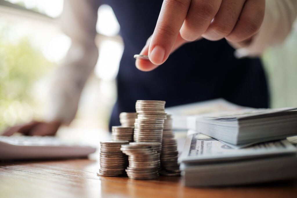 A person is stacking coins on top of each other on a table.