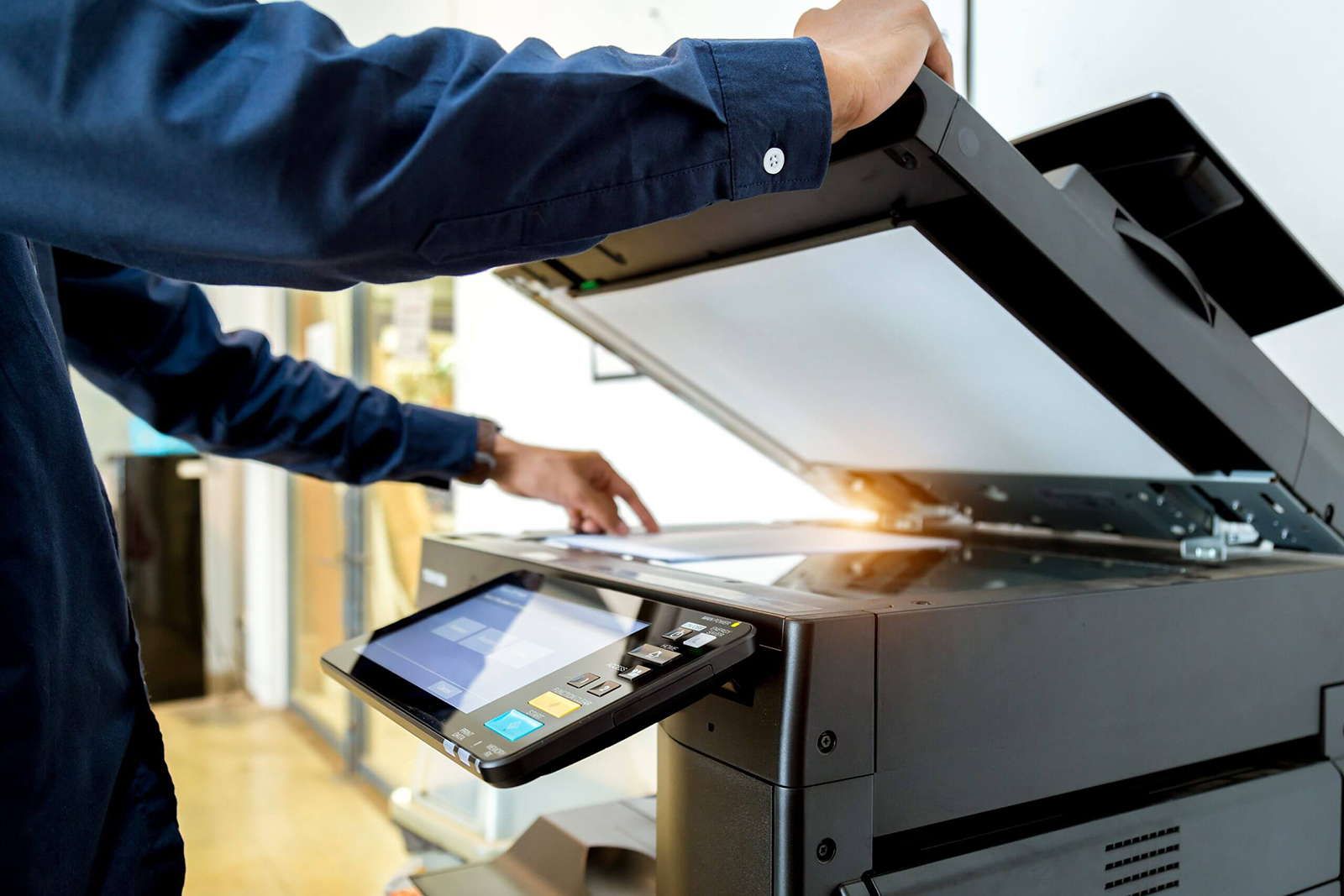 A man is using a printer to scan a piece of paper.