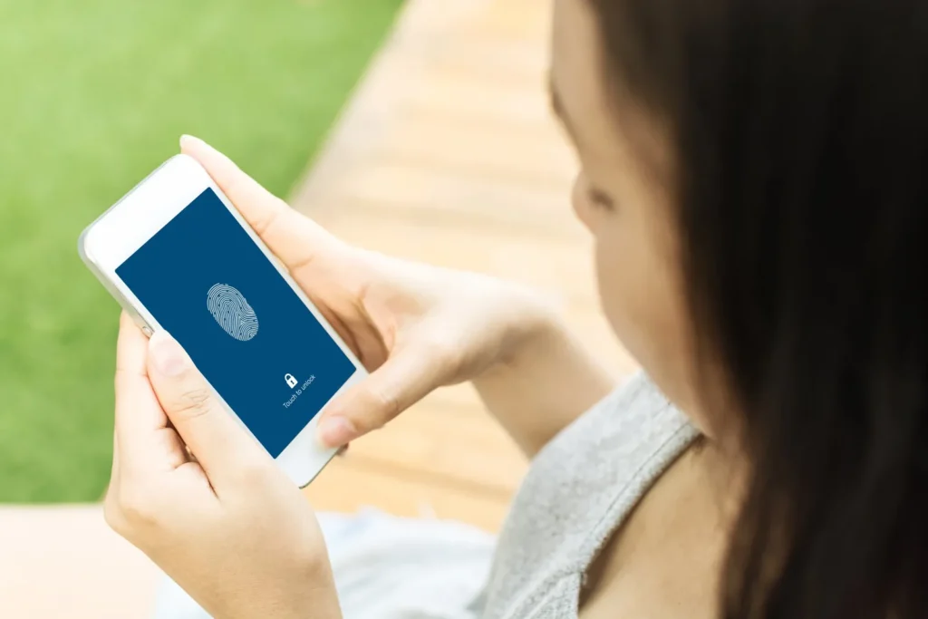 A woman is holding a cell phone with a fingerprint on the screen.
