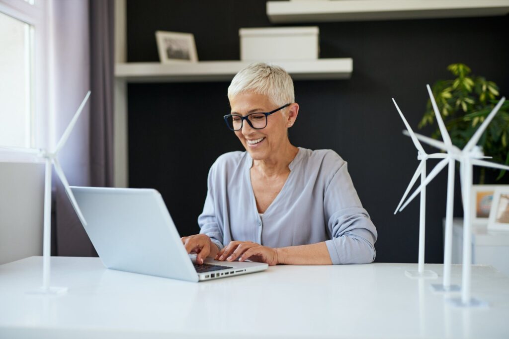 A woman is sitting at a desk using a laptop computer.