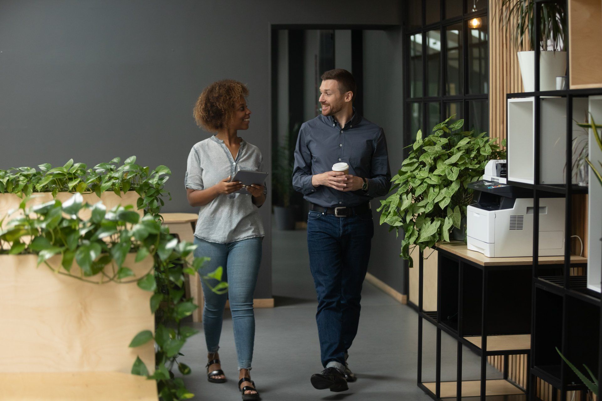 A man and a woman are walking down a hallway in an office.