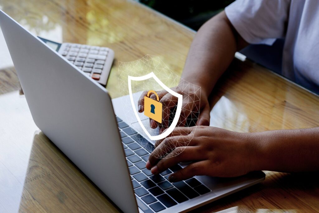 A person is typing on a laptop computer with a padlock on the screen.