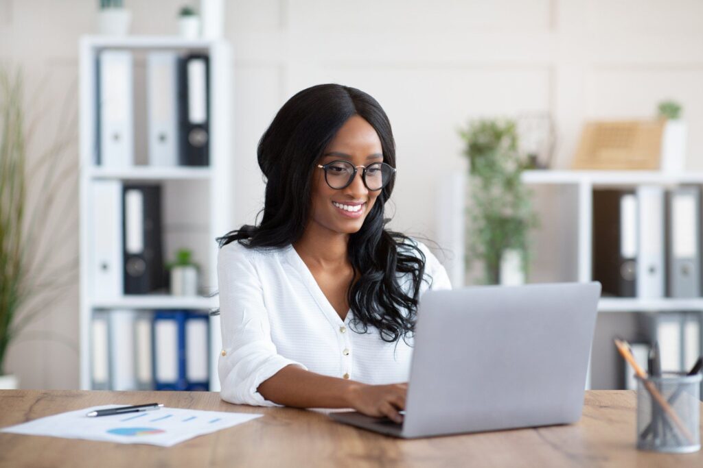 A woman is sitting at a desk using a laptop computer.