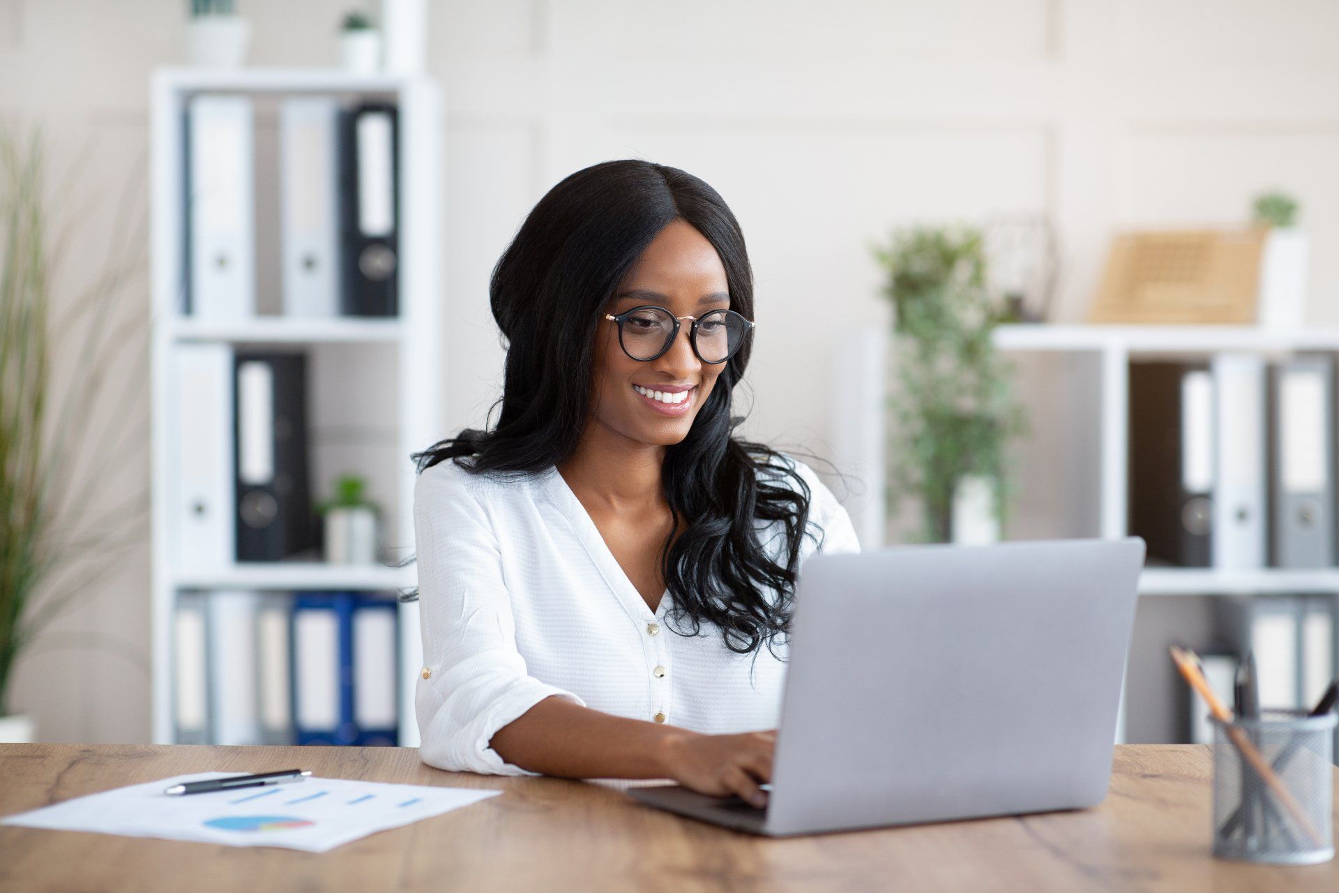 A woman is sitting at a desk using a laptop computer.