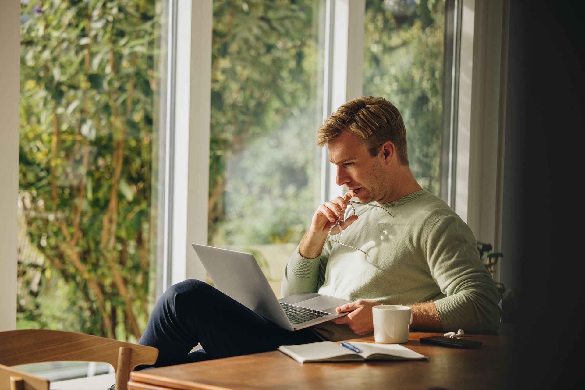 A man is sitting at a table using a laptop computer.
