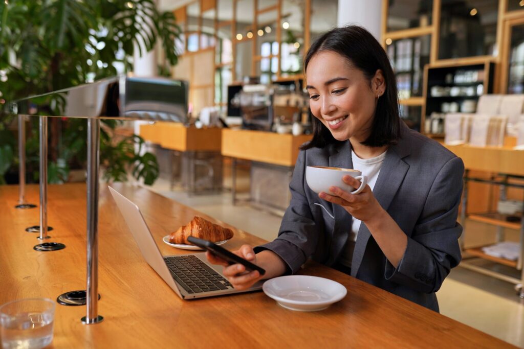A woman is sitting at a table with a laptop and a cup of coffee.