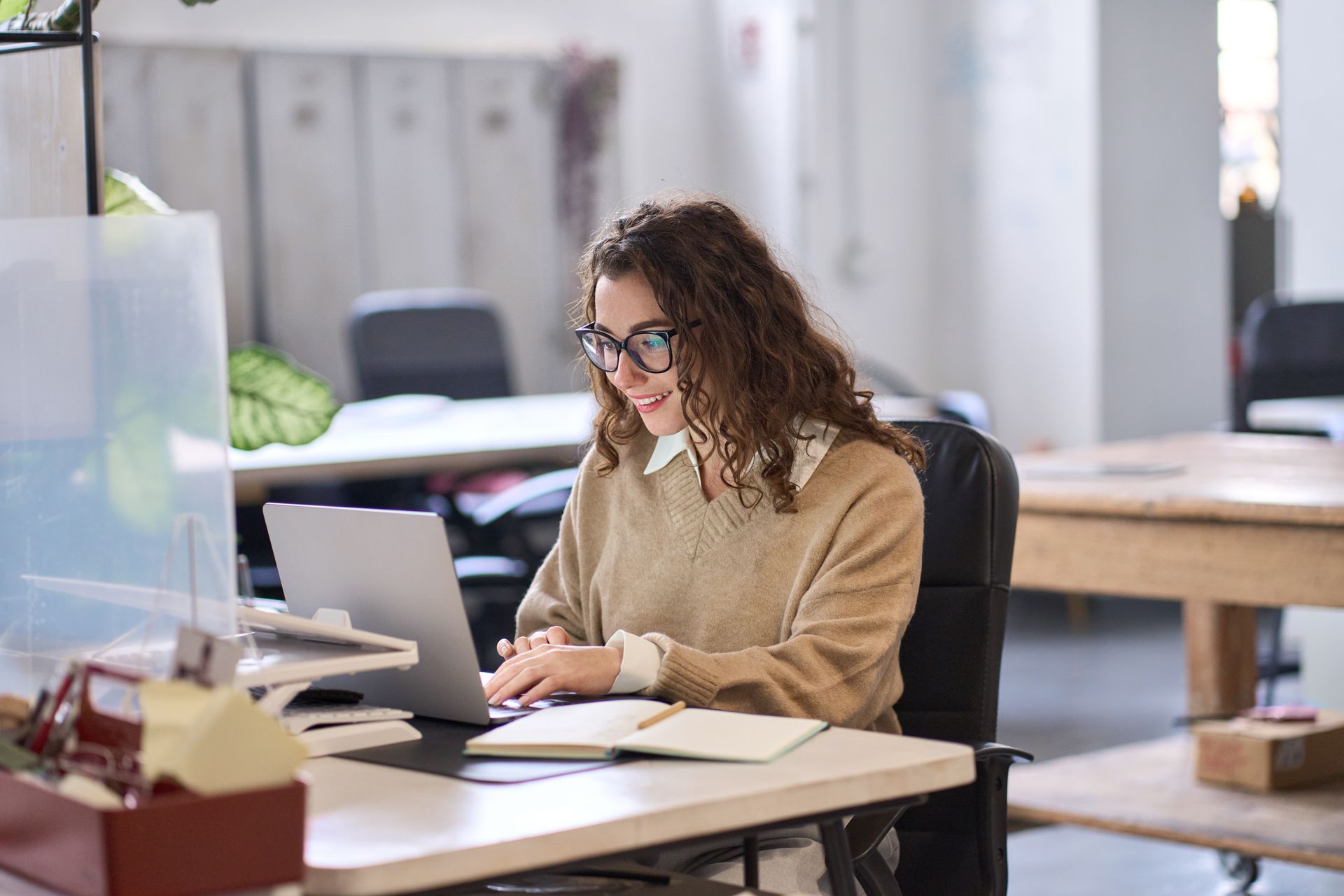 A woman is sitting at a desk using a laptop computer.