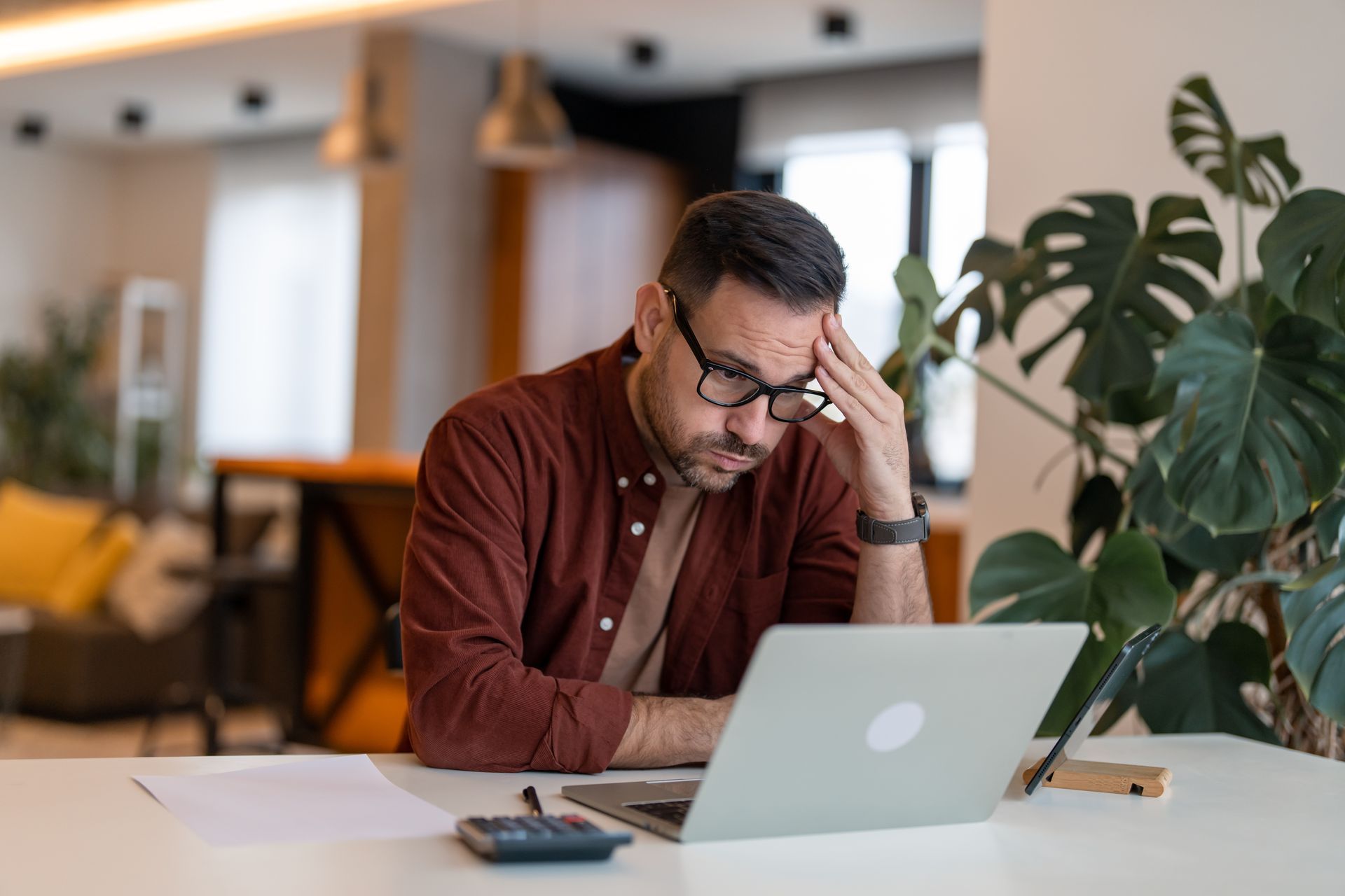 A man is sitting at a table using a laptop computer.
