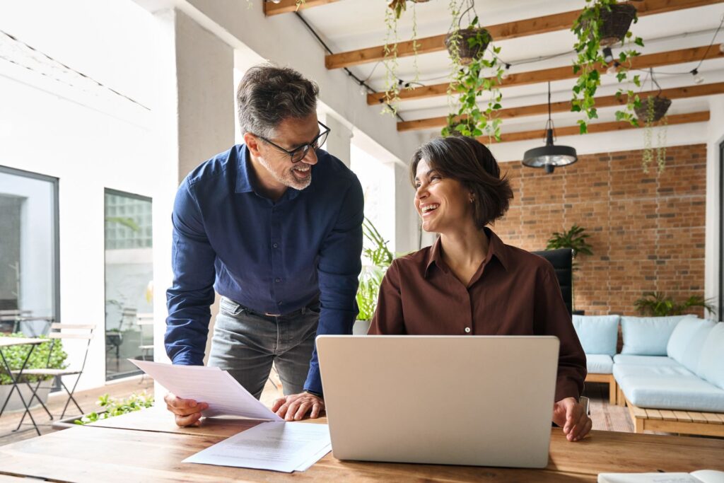 A man and a woman are looking at a laptop computer.