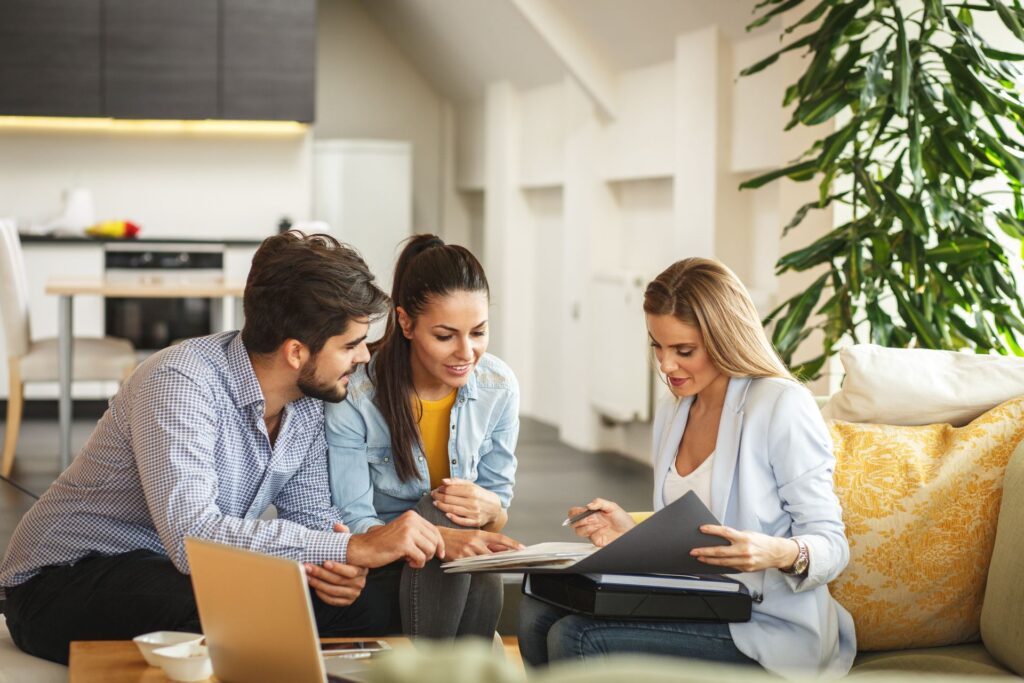A man and a woman are sitting on a couch looking at a document.