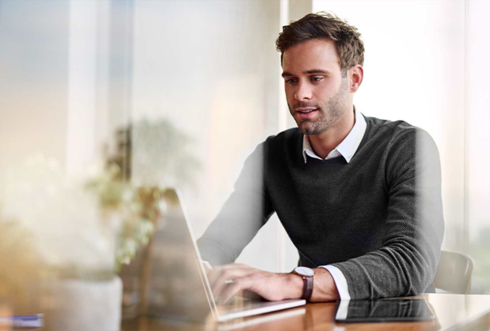 A man is sitting at a desk using a laptop computer.