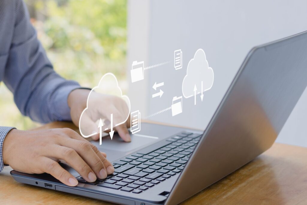 A person is typing on a laptop computer on a wooden table.