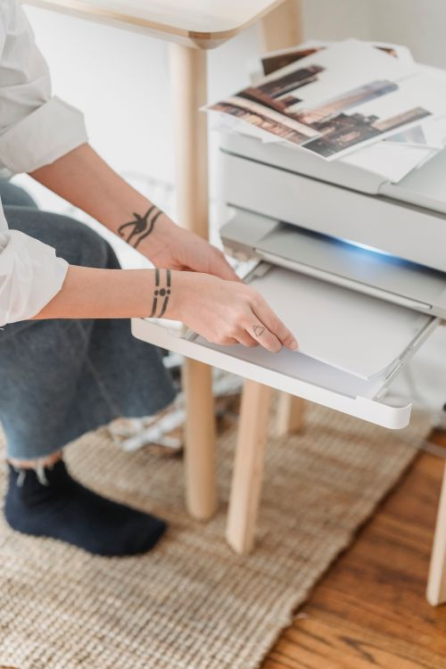 A businesswoman collecting confidential printed documents from an office printer output tray